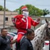 Policial fantasiado de Papai Noel, montado em cavalo branco com manchas marrons