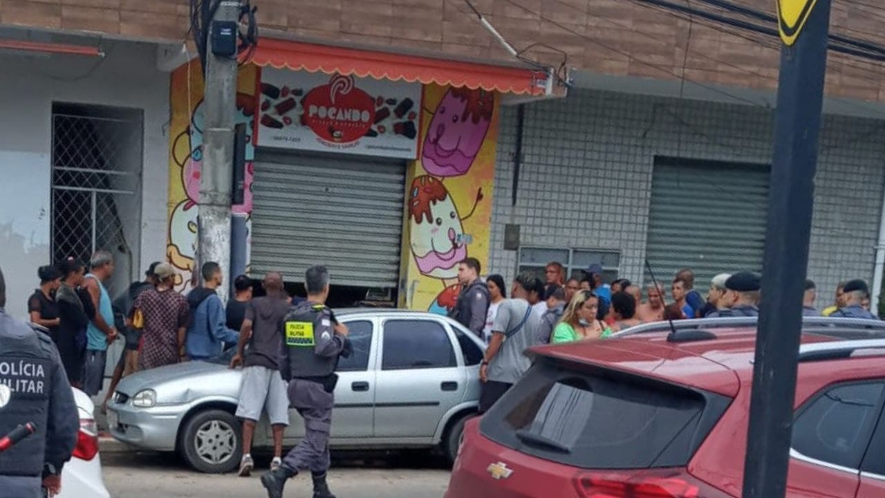 Multidão de pessoas paradas olhando homem baleado em frente a uma sorveteria