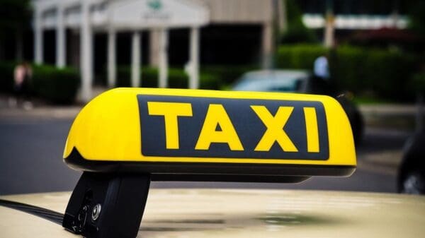 Foto com o letreiro de Taxi que fica acima do veiculo na cor amarela com fundo desfocado