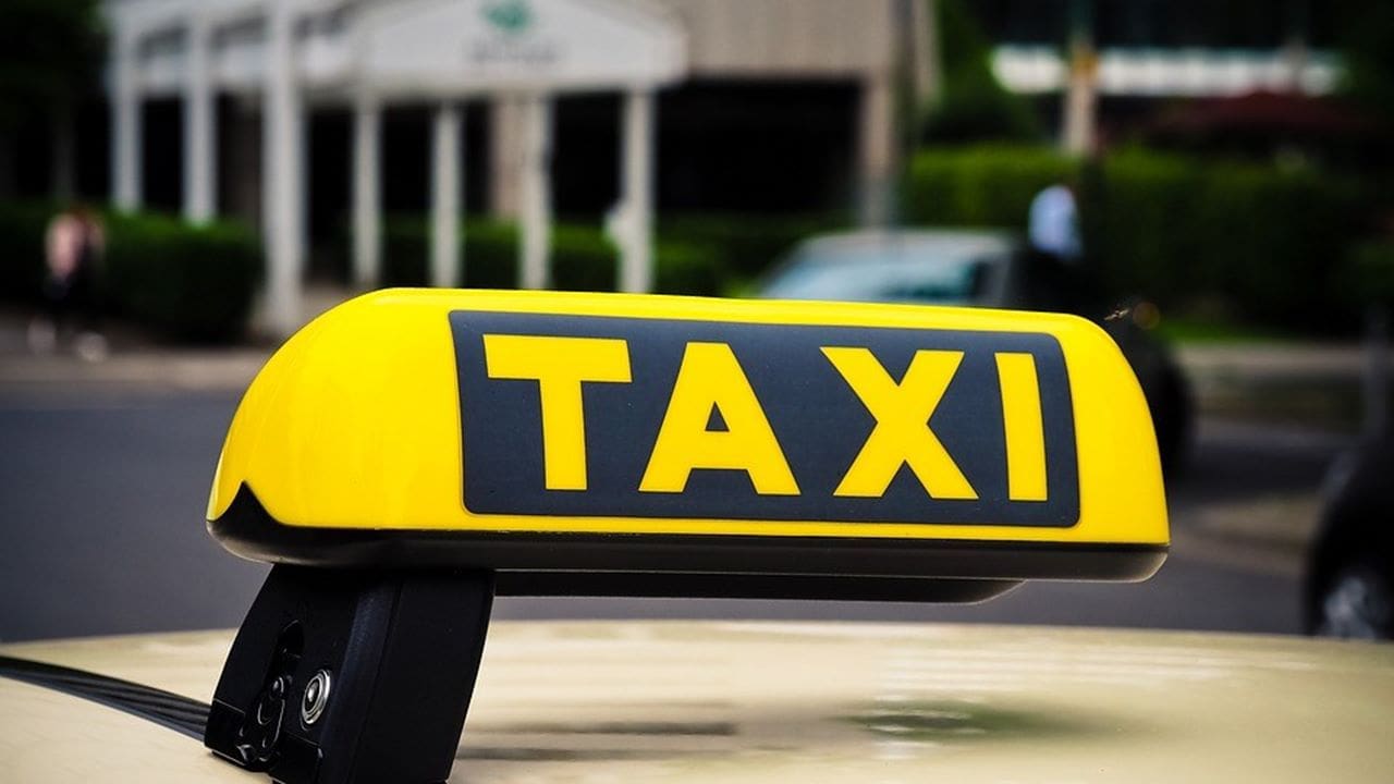 Foto com o letreiro de Taxi que fica acima do veiculo na cor amarela com fundo desfocado