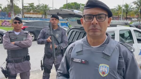 Sargento da 14ª Cia Ind. Mauricio Sousa, relatando a prisão de um traficante e logo atras dois Militares em pé ao lado da viatura segurando sus armas