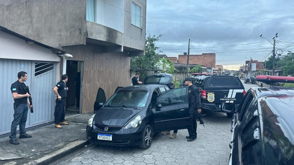 Foto de policiais civis próximo de um automóvel Honda Fit fazendo buscas por materiais ilícitos