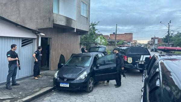 Foto de policiais civis próximo de um automóvel Honda Fit fazendo buscas por materiais ilícitos