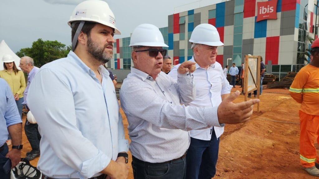 Foto de 3 homens com capacetes de proteção de obras da construção civil, conversando em meio a obra do Complexo Viário de Carapina a foto foi tirada durante visita do Governador Renato Casagrande e o secretário de Estado de Mobilidade e Infraestrutura, Fábio Damasceno o terceiro homem é o engenheiro chefe da obra