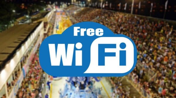 Arte de divulgação do Wi-fi gratuito oferecido pela Prefeitura de Vitória, uma logo em azul e branco escrito free Wi-Fi e ao fundo desfocada a imagem aérea do desfile de uma escola de samba no Sambão do Povo em Vitória