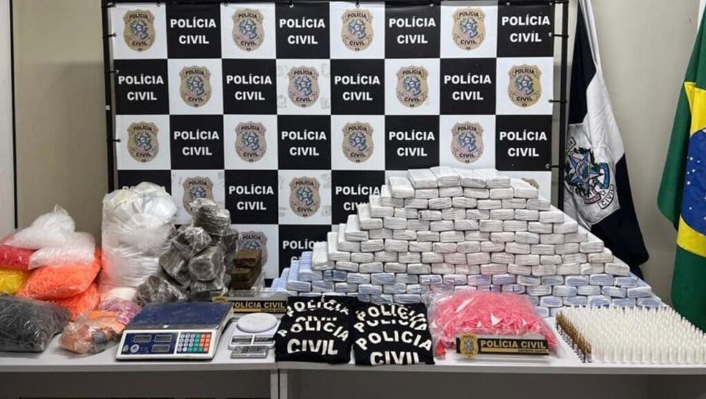 Foto de divulgação da apreensão de drogas realizada em Cariacica, sobre uma mesa branca 136kg de maconha, 31 frascos de fentanil, 2.500 pinos de cocaína cheios, milhares de pinos vazios, 13kg de mistura para cocaína, 10 camisas estampadas com o nome da Polícia Civil, 02 balanças de precisão.