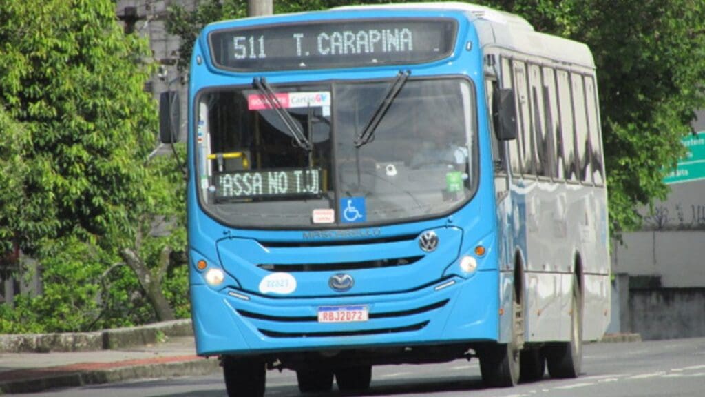 Ônibus azul do sistema Transcol, transitando em uma rua arborizada com o letreiro marcando Terminal Carapina