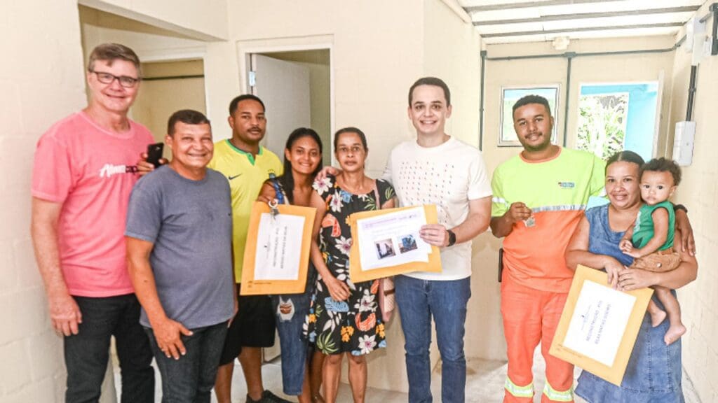 Foto de 3 famílias com documentos e chaves das novas casas reconstruídas pelo projeto reconstrução, e no centro da foto o Prefeito de Vitória,