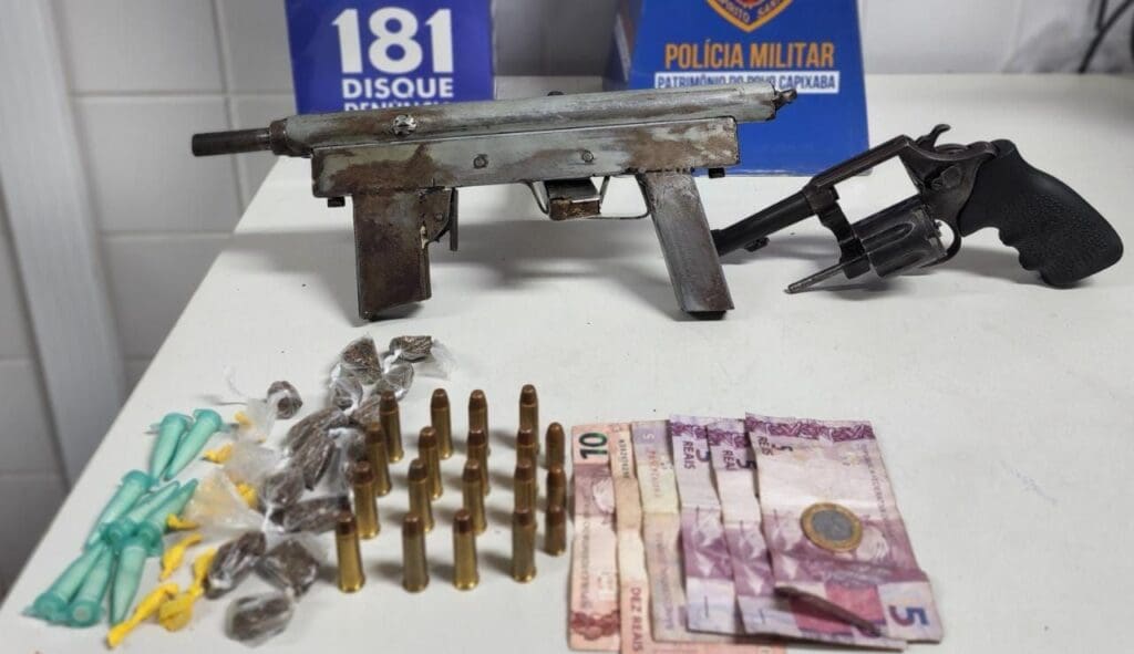 Foto de divulgação de apreensão de drogas e armas de fogo sobre uma mesa branca um revólver calibre .38, uma metralhadora caseira calibre .380, munições de ambos os calibres, além de pedras de crack, pinos de cocaína, buchas de maconha e 41 reais em espécie