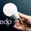 Uma mão segurando uma lâmpada acesa, ao fundo um cenario escuro e a sigla EDP e o logo da compania