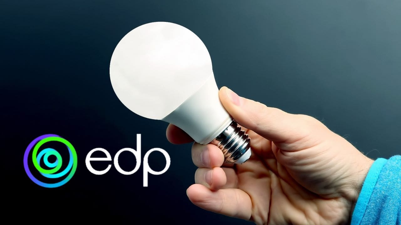 Uma mão segurando uma lâmpada acesa, ao fundo um cenario escuro e a sigla EDP e o logo da compania