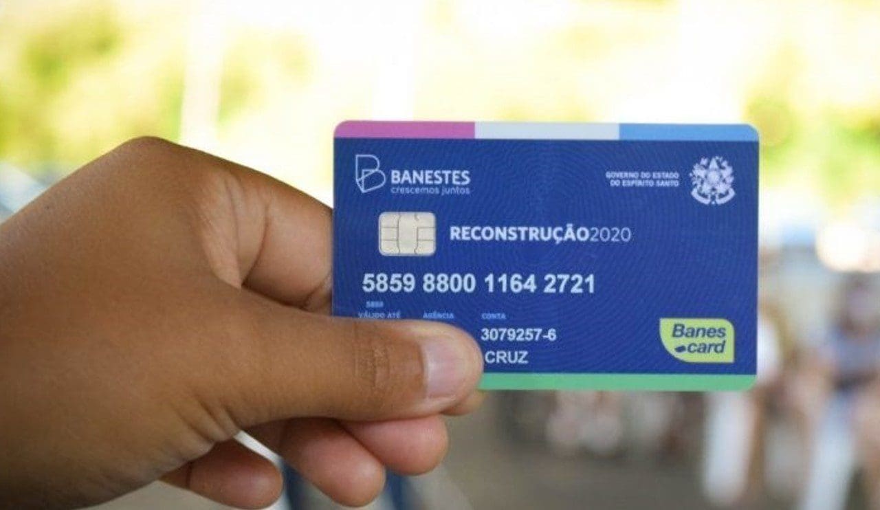 Imagem de uma mão segurando um cartão benefício do Governo do ES, com o fundo desfocado