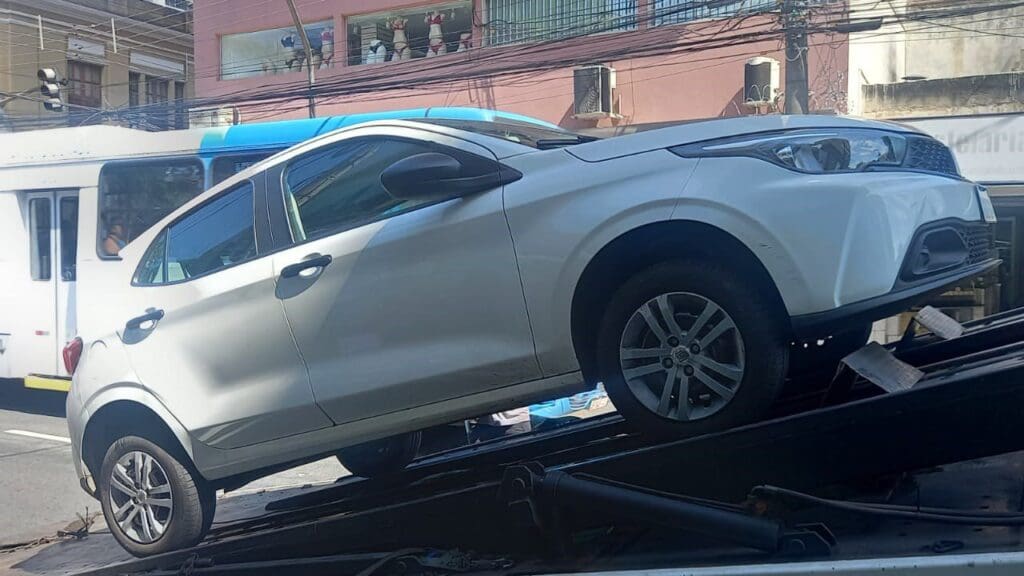 Foto de um veículo modelo Fiat Argo cor branca, sendo colocado em cima de um guincho