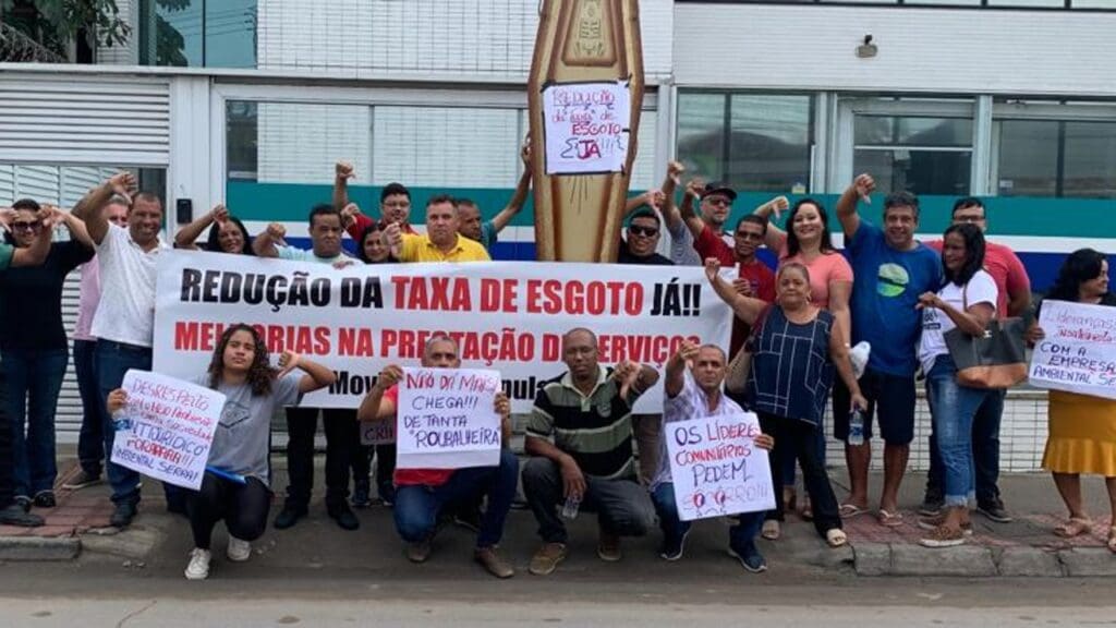 Manifestantes com faixas e cartazes em frente ao prédio onde fica a sede da empresa que cuida do esgoto da cidade da Serra (Ambiental Serra)