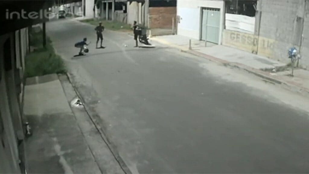 Foto em uma rua deserta no bairro de Jacaraípe por volta da 1:30h da madrugada, dois bandidos rendem um entregador que estava de moto e roubam a motocicleta e o bag onde estavam os lanches um dos ladrões esta proximo a vítima que assustada esta abaixada deixando o capacete no chão, enquanto o outro ladrão ja com a bag de entregador segura a motocicleta