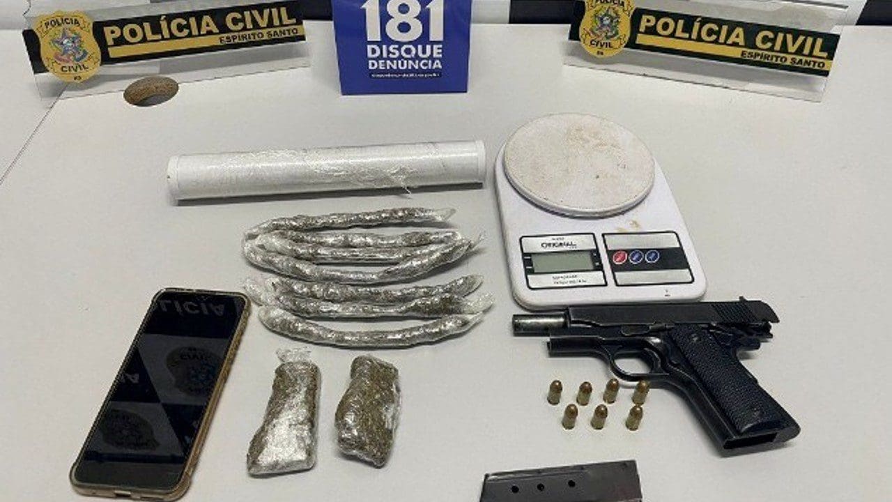Foto sobre uma mesa uma pistola .380, 7 munições, um carregador, porções de maconha embaladas para venda, material para embalar drogas e uma balança de precisão.