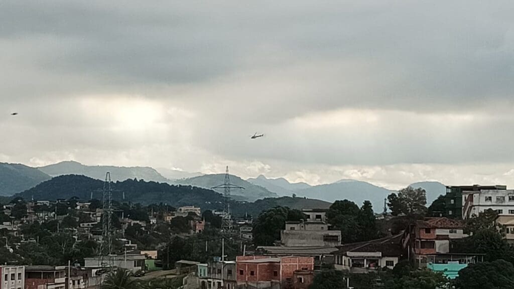 Foto de um helicopter sobrevoando um bairro de Cariacica apos atentado contra um Policial Militar