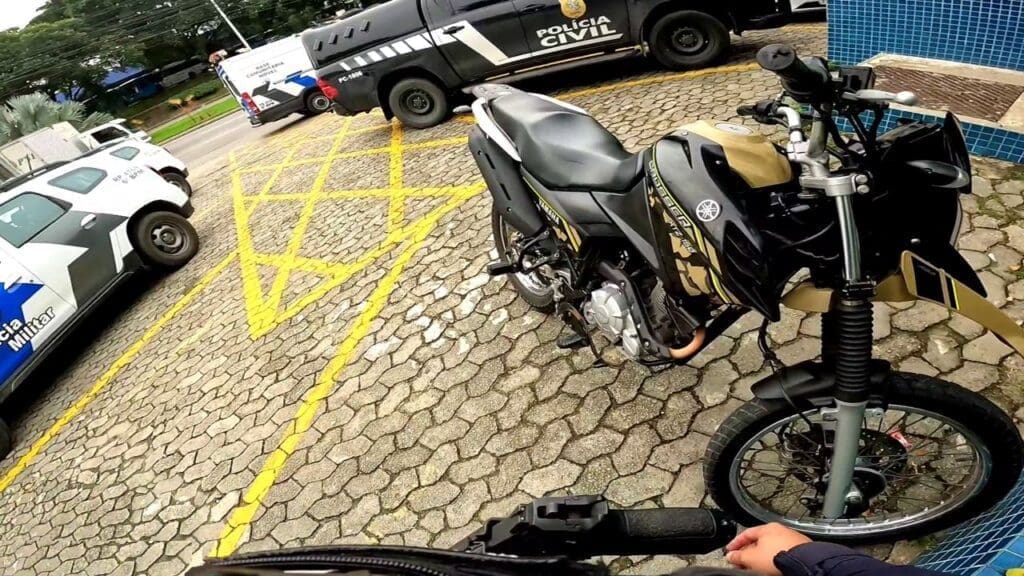 Patio da 3ª Delegacia Regional situada Serra, com viaturas e a motocicleta da Yamaha estacionada, com um Agente da GCM parado proximo ao veiculo