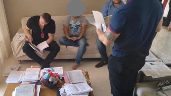 Foto da Polícia Civil em uma sala analisando documentos, durante uma prisão de dois homens que realizavam golpes imobiliários no estado do Espirito Santo.