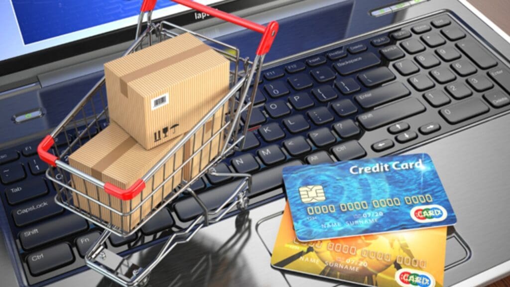 Foto de um mini carrinho ao lado de cartões de crédito, sob um notebook.