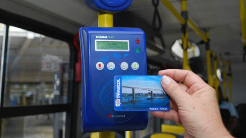 Foto de uma pessoa segurando o vale transporte para ultrapassar a catraca.