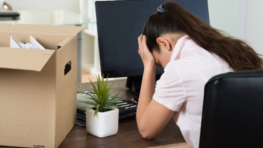 Foto de uma mulher com a cabeça baixa, por saber que perdeu o emprego