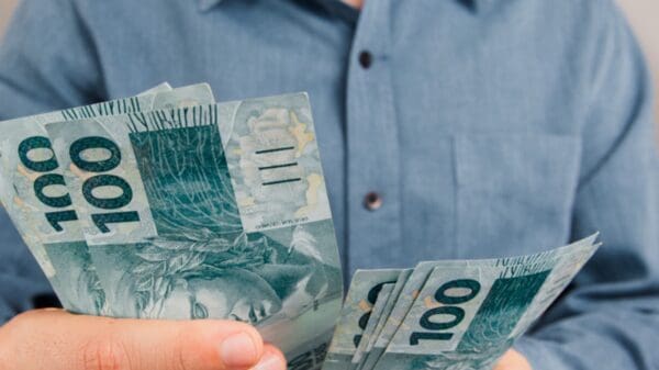 Foto de uma pessoa contando notas de 100 reais - empréstimo