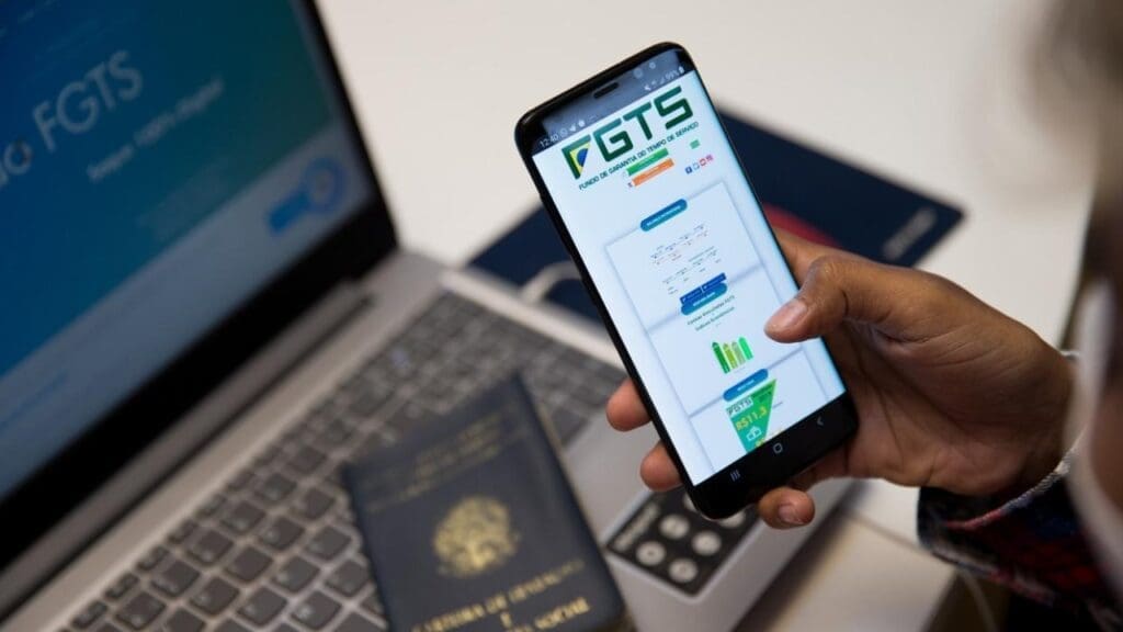 Foto de uma pessoa acessando o site do FGTS no PC e celular