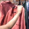 Mulher segurando camisa em cabide