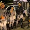 Foto do Sargento Mauricio Sousa apresentando outros 4 policiais militares que estão parados em frente a uma viatura da Policia Militar e junto com os militares o cão farejador Apollo.