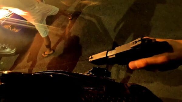 Foto: Um agente da Gurda da Serra segurando uma pistola enquanto um jovem está com as pernas afastadas e com as mãos na cabeça, aguardando ser revistado