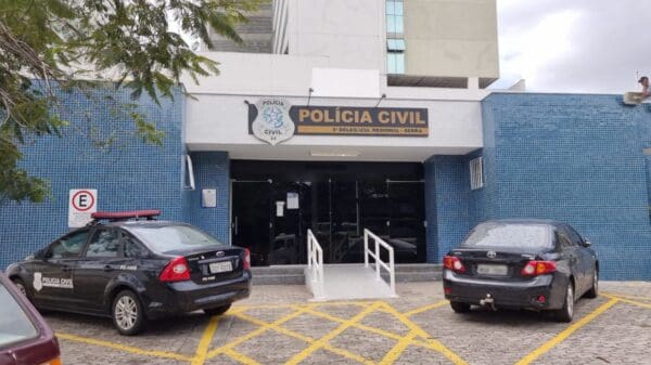 Foto da entrada da sede 3ª Delegacia Regional situada na Serra, com uma viatura da Polícia Civil, e outro veículo estacionados em seu patio