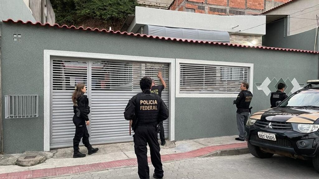 4 agentes da Policia Federal em frente a uma casa, prontos para cumprir um mandado de prisão