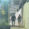 Policial Militar levando uma mulher acusada de falsificar documentos, ambos de costas em frente em frente a um portão da 3ª Delegacia Regional da Serra.