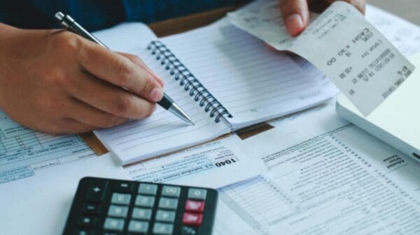 Foto de uma pessoa calculando suas contas e dívidas