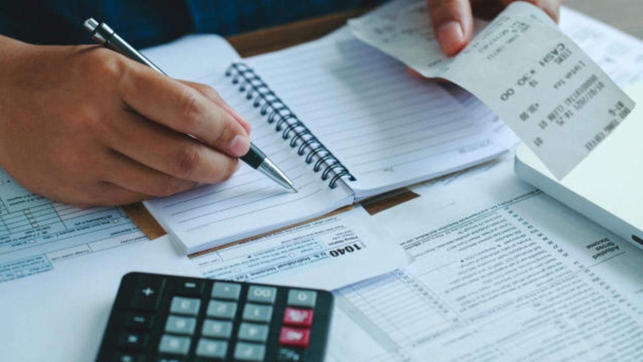 Foto de uma pessoa calculando suas contas e dívidas
