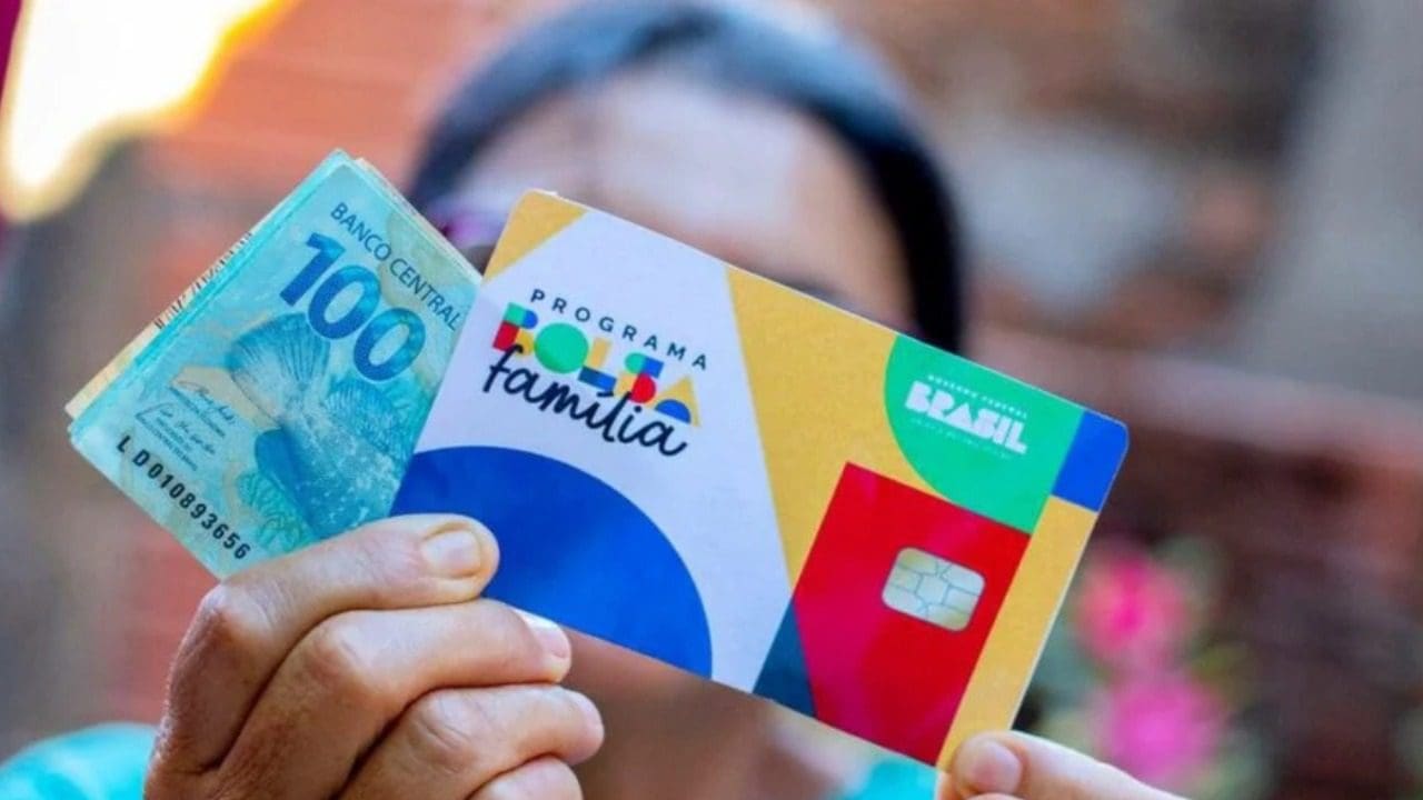 Foto de uma pessoa segurando um cartão do bolsa família e dinheiro recebido