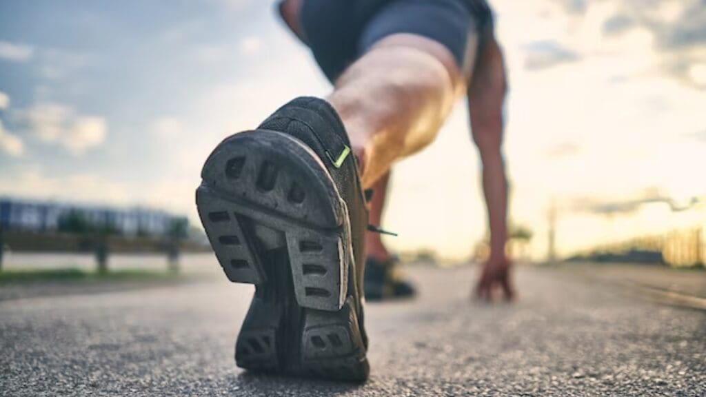 foto mostra corredor se preparando para correr desfocado e foca no tenis