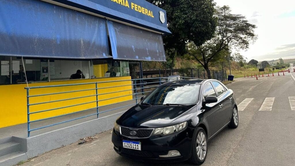 Veículo KIA Cerato, estacionado em frente a um posto da Polícia Rodoviaria Federal