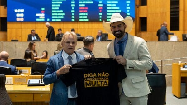 Foto do deputado Pablo Muribeca segurando uma camiseta com os dizeres Diga Não a indústria da multa, juntamente com o deputado Sergio Meneguelli, durante seção da Assembleia Legislativa do Espírito Santo