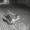 Imagem de uma câmera de segurança flagrando um homem (catador de materiais recicláveis), furtando uma grelha de proteção da rede fluvial de em uma rua residencial, sem movimento durante a madrugada