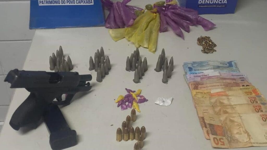 Sobre uma mesa branca uma pistola calibre 9mm com um carregador contendo 11 munições intactas, 38 pinos de cocaína, um papelote pequeno de cocaína, 19 buchas de maconha, três buchas pequenas de maconha, 14 pedras de crack e 314 reais em espécie.