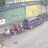 Foto de uma rua tranquila, com 10 motocicletas estacionadas proximo a guia, enquanto um ladrão força a ignição para roubar o veiculo.