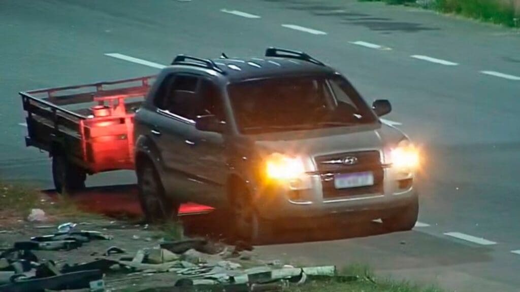 Foto com um veículo estacionado em uma via, com um carrinho (caçamba), realizando descarga de lixo em local inapropriado.