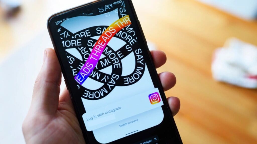Foto de uma mão segurando um celular aberto na rede social Threads