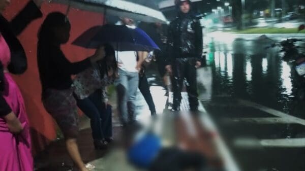 Mulheres com sombrinhas ajudando a proteger homem baleado da chuva Av. Região Sudeste, no bairro Barcelona