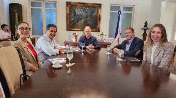 Foto do governador Renato Casagrande sentado à mesa, juntamente com representantes do Grupo Boticário