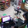 Um homem com uma das mãos na cintura simulando estar armado, roubando uma loja de conveniência para assalto