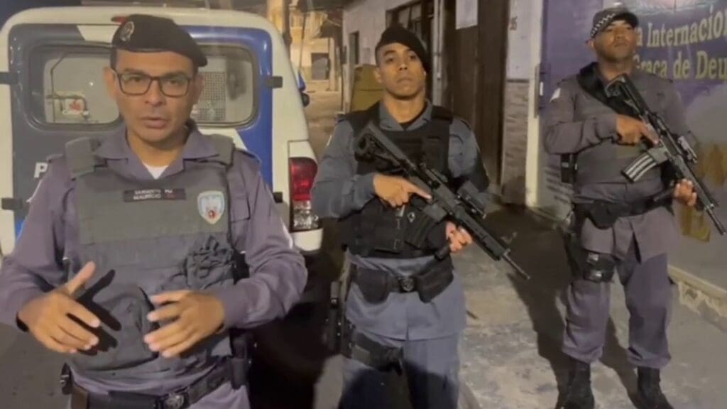 Foto com 3 militares em frente a uma viatura da PM.