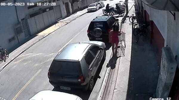 Imagem de uma camera de segurança, onde é possível ver a ação de dois bandidos furtando uma motocicleta em uma rua, movimentada.
